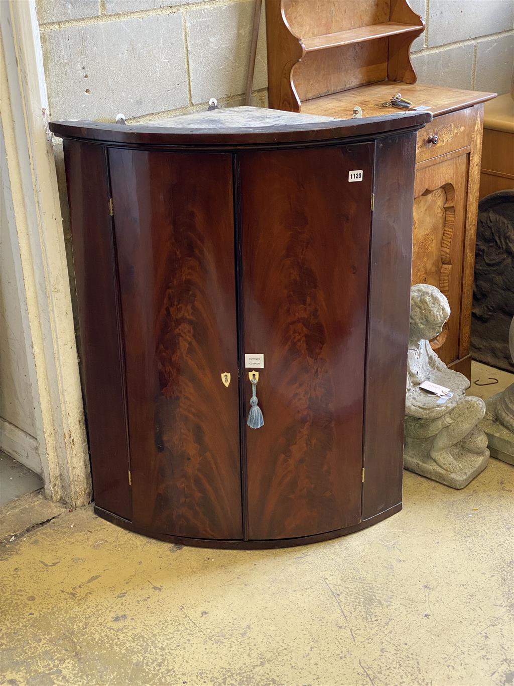 A Regency mahogany bow fronted hanging corner cupboard, width 80cm, depth 56cm, height 98cm